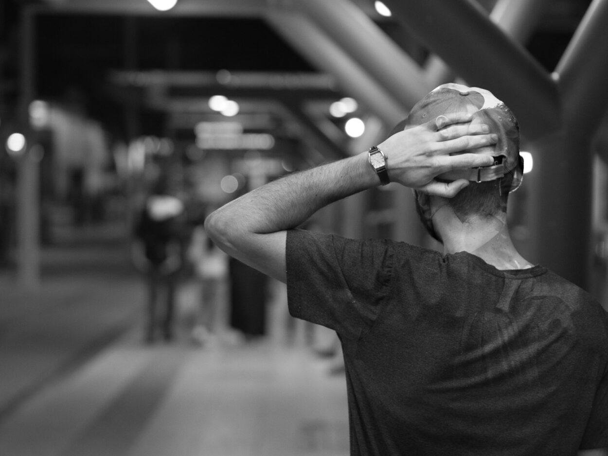 a man in a black shirt is covering his face with his hands